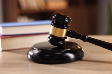 Photo of Judge's gavel and books on wooden table indoors, selective focus