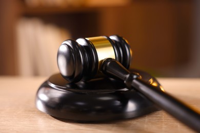 Photo of Judge's gavel on wooden table against blurred background, closeup
