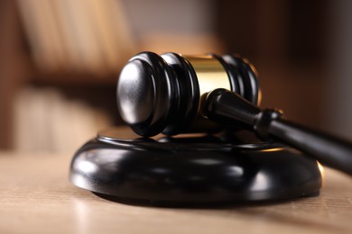 Photo of Judge's gavel on wooden table against blurred background, closeup
