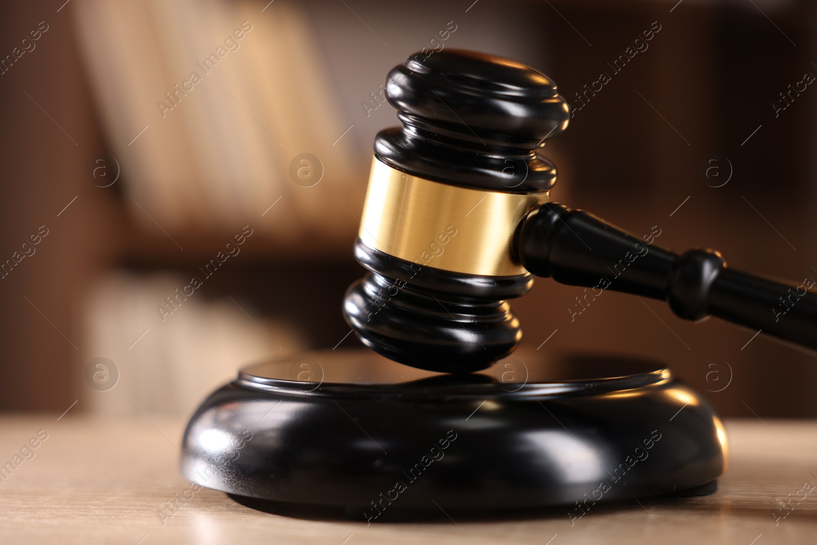 Photo of Judge's gavel on wooden table against blurred background, closeup