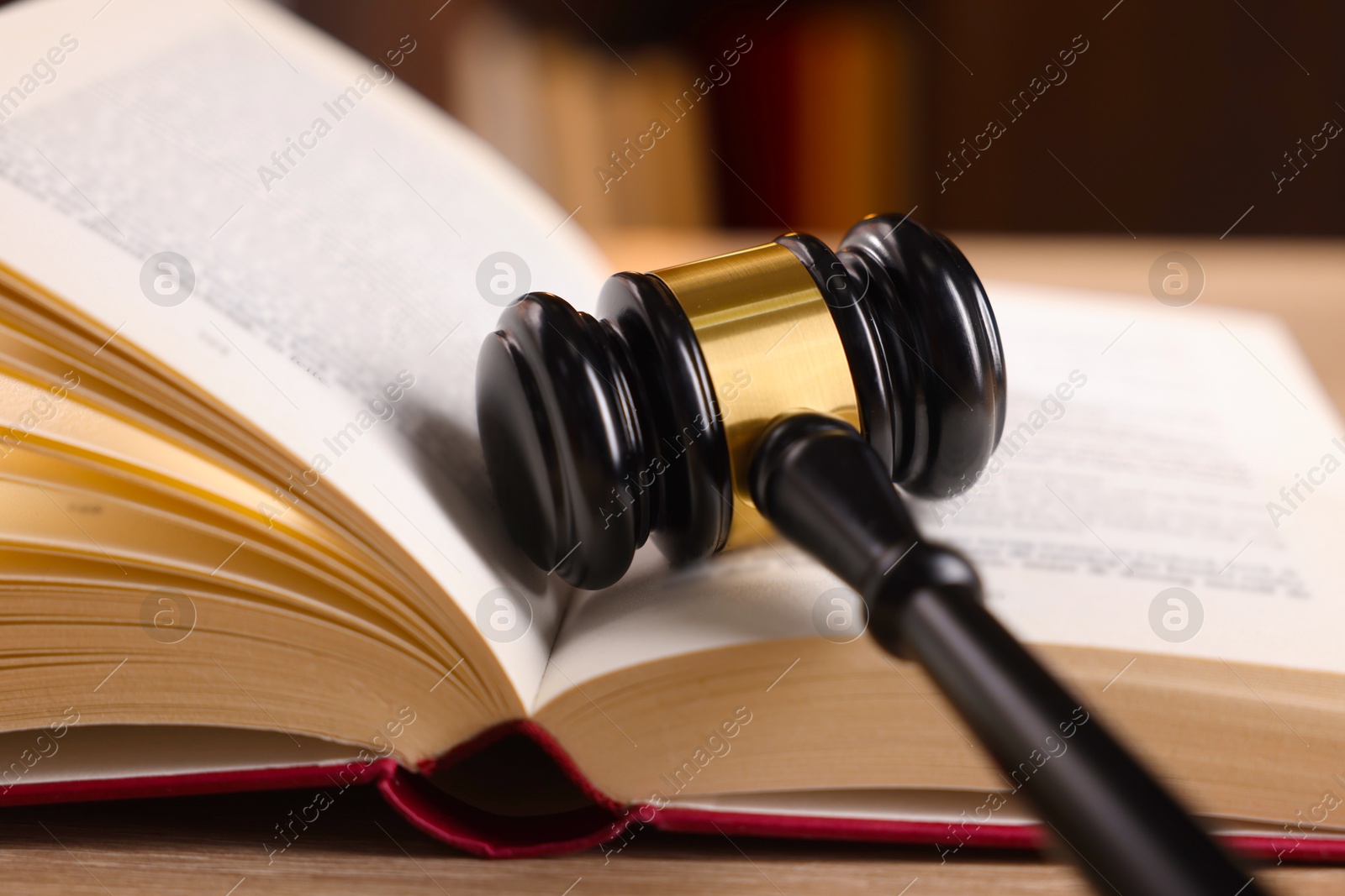 Photo of Judge's gavel and book on wooden table indoors, closeup