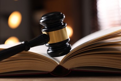 Photo of Judge's gavel and book on wooden table indoors, closeup