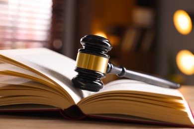 Photo of Judge's gavel and book on wooden table indoors, closeup