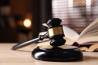 Photo of Judge's gavel and book on wooden table indoors, selective focus
