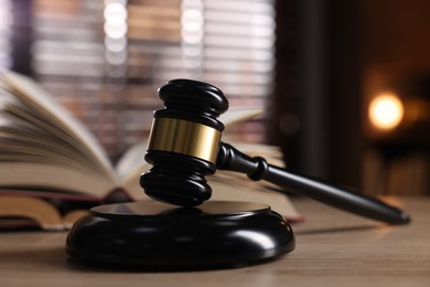 Photo of Judge's gavel and book on wooden table indoors, selective focus