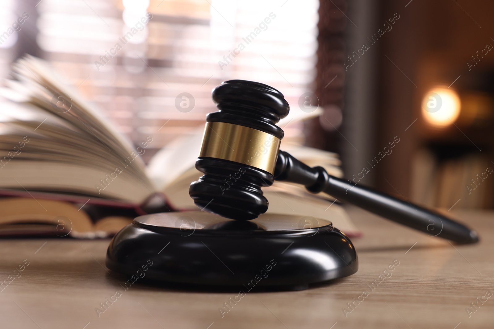 Photo of Judge's gavel and book on wooden table indoors, selective focus