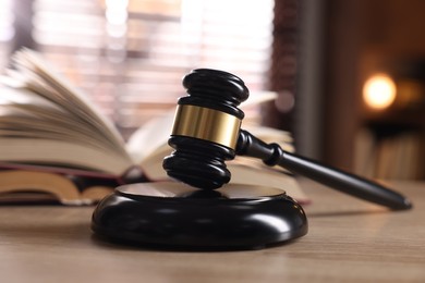 Photo of Judge's gavel and book on wooden table indoors, selective focus