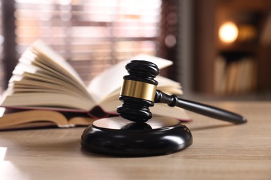 Photo of Judge's gavel and book on wooden table indoors, selective focus