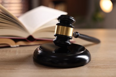 Photo of Judge's gavel and book on wooden table indoors, selective focus
