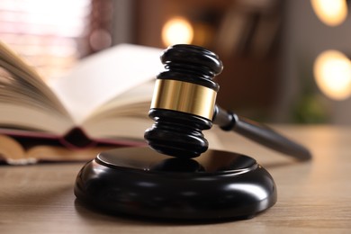 Photo of Judge's gavel and book on wooden table indoors, selective focus