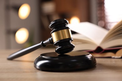 Photo of Judge's gavel and book on wooden table indoors, selective focus