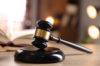 Photo of Judge's gavel and book on wooden table indoors, selective focus