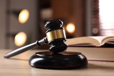 Photo of Judge's gavel and book on wooden table indoors, selective focus