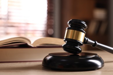 Photo of Judge's gavel and book on wooden table indoors, selective focus