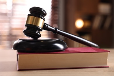 Photo of Judge's gavel and book on wooden table indoors, closeup