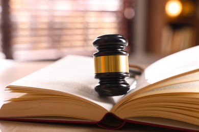 Photo of Judge's gavel and book on wooden table indoors, closeup