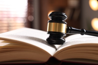 Photo of Judge's gavel on book against blurred background, closeup