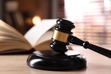 Photo of Judge's gavel and book on wooden table indoors, selective focus