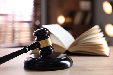 Photo of Judge's gavel and book on wooden table indoors, selective focus
