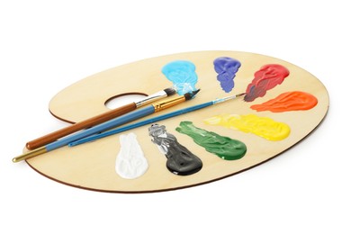 Photo of Wooden palette with paints and brushes isolated on white