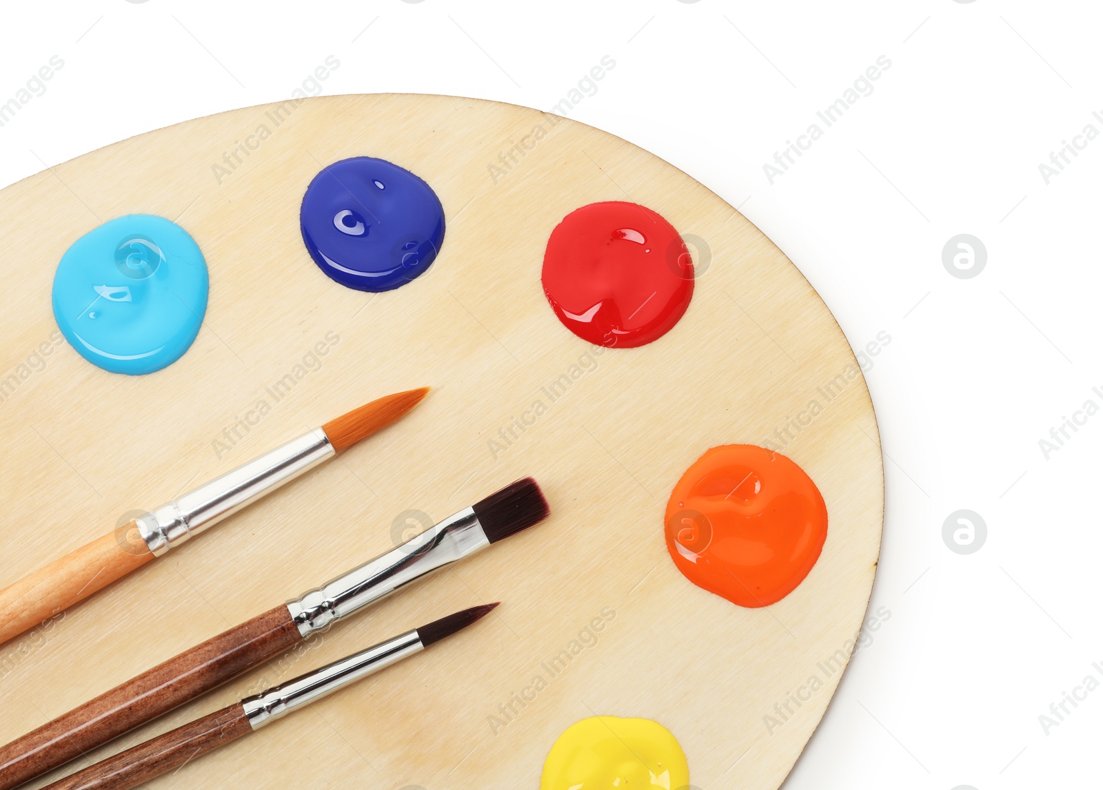Photo of Wooden palette with paints and brushes isolated on white, top view