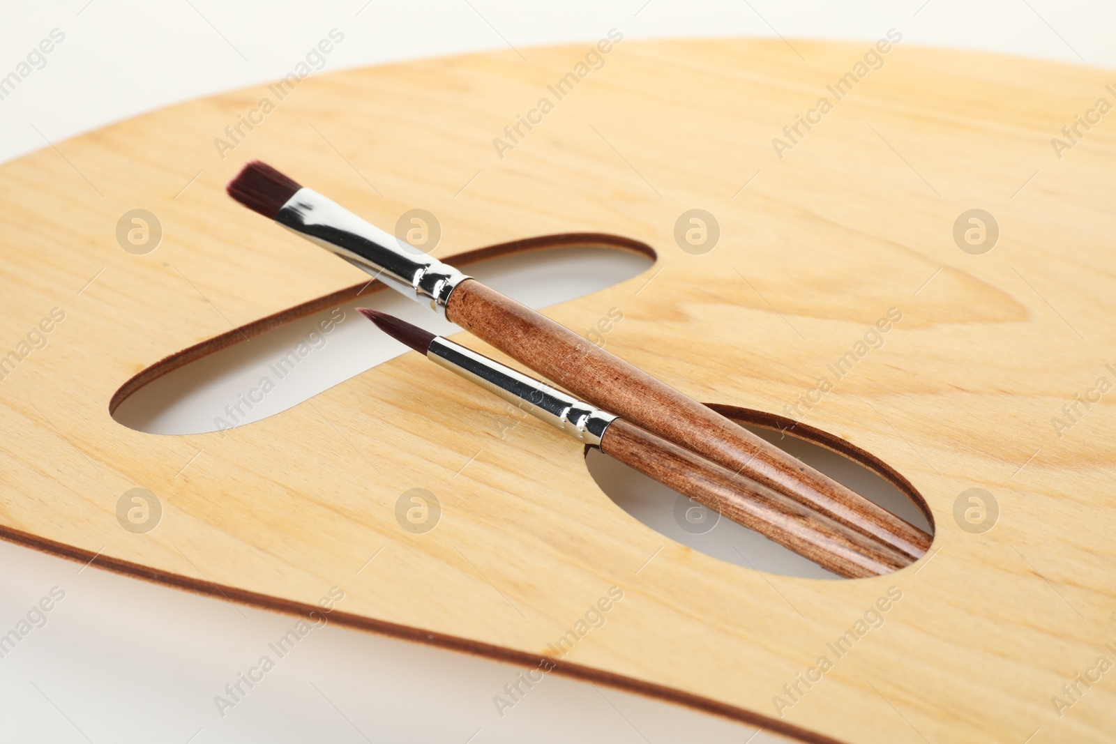 Photo of Wooden palette and brushes isolated on white