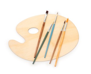 Photo of Wooden palette and brushes isolated on white, top view
