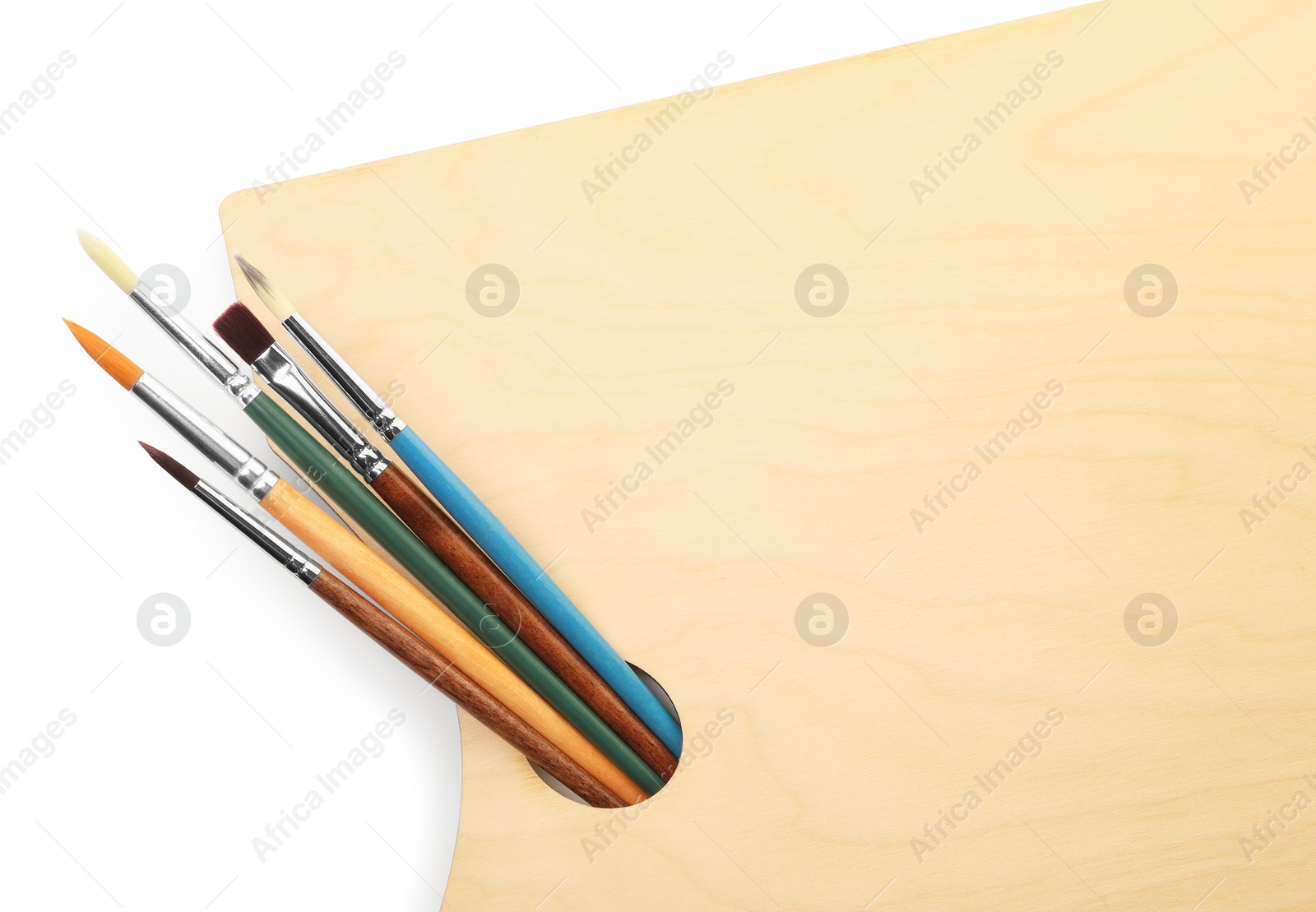 Photo of Wooden palette and brushes isolated on white, top view