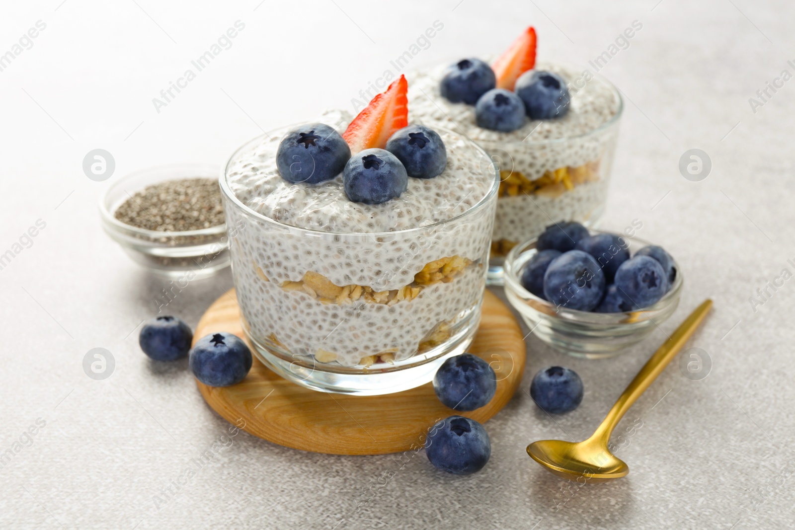 Delicious pudding with chia seeds, yogurt, blueberries, granola and strawberry on light grey table, closeup. Superfood Photo of Delicious pudding with chia seeds, yogurt, blueberries, granola and strawberry on light grey table, closeup. Superfood