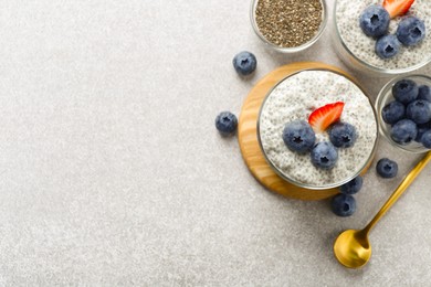 Photo of Superfood. Delicious pudding with chia seeds, yogurt, blueberries, granola and strawberry on light grey table, flat lay. Space for text