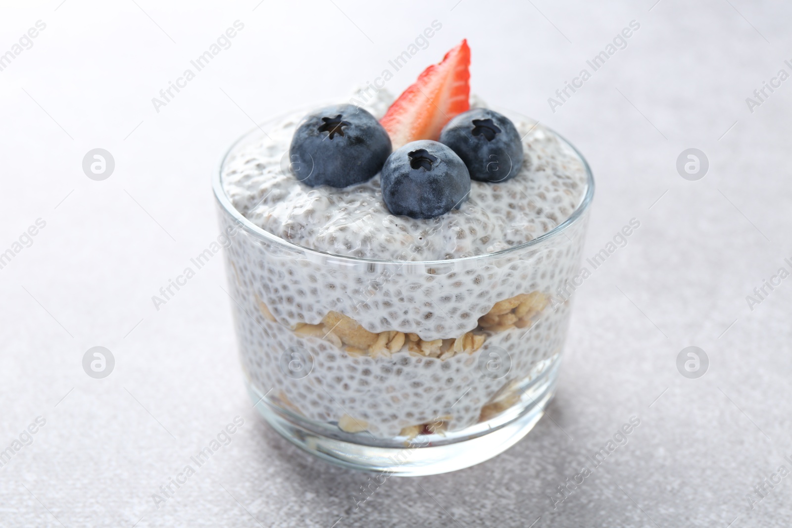 Delicious pudding with chia seeds, yogurt, blueberries, granola and strawberry on light grey table, closeup. Superfood Photo of Delicious pudding with chia seeds, yogurt, blueberries, granola and strawberry on light grey table, closeup. Superfood