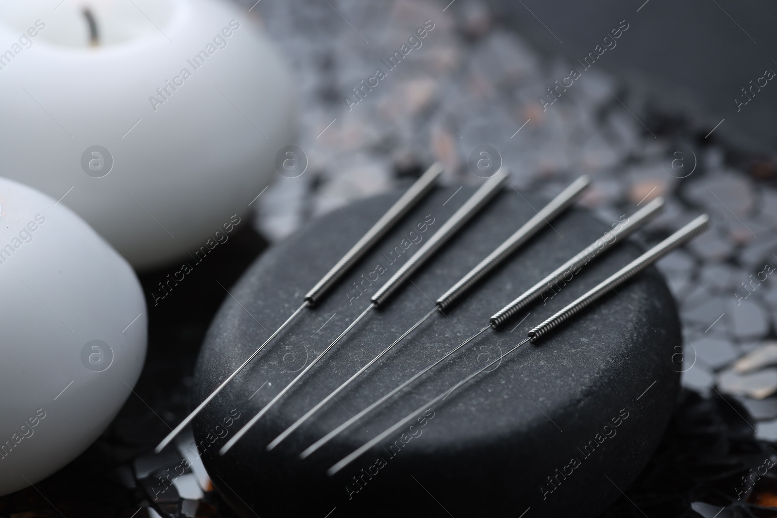 Acupuncture needles, spa stone and candles on dark textured background, closeup Photo of Acupuncture needles, spa stone and candles on dark textured background, closeup