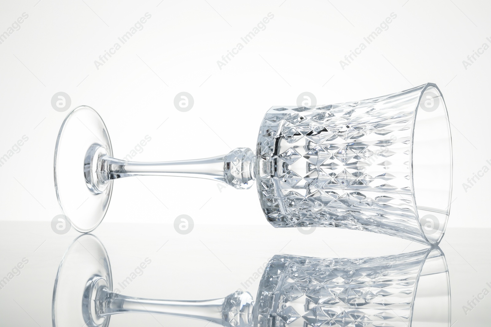 One empty clean glass on mirror surface against white background Photo of One empty clean glass on mirror surface against white background