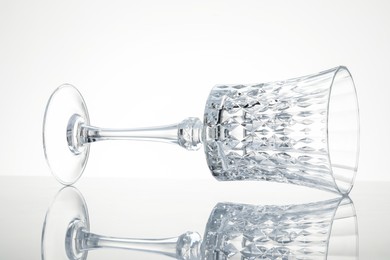 Photo of One empty clean glass on mirror surface against white background