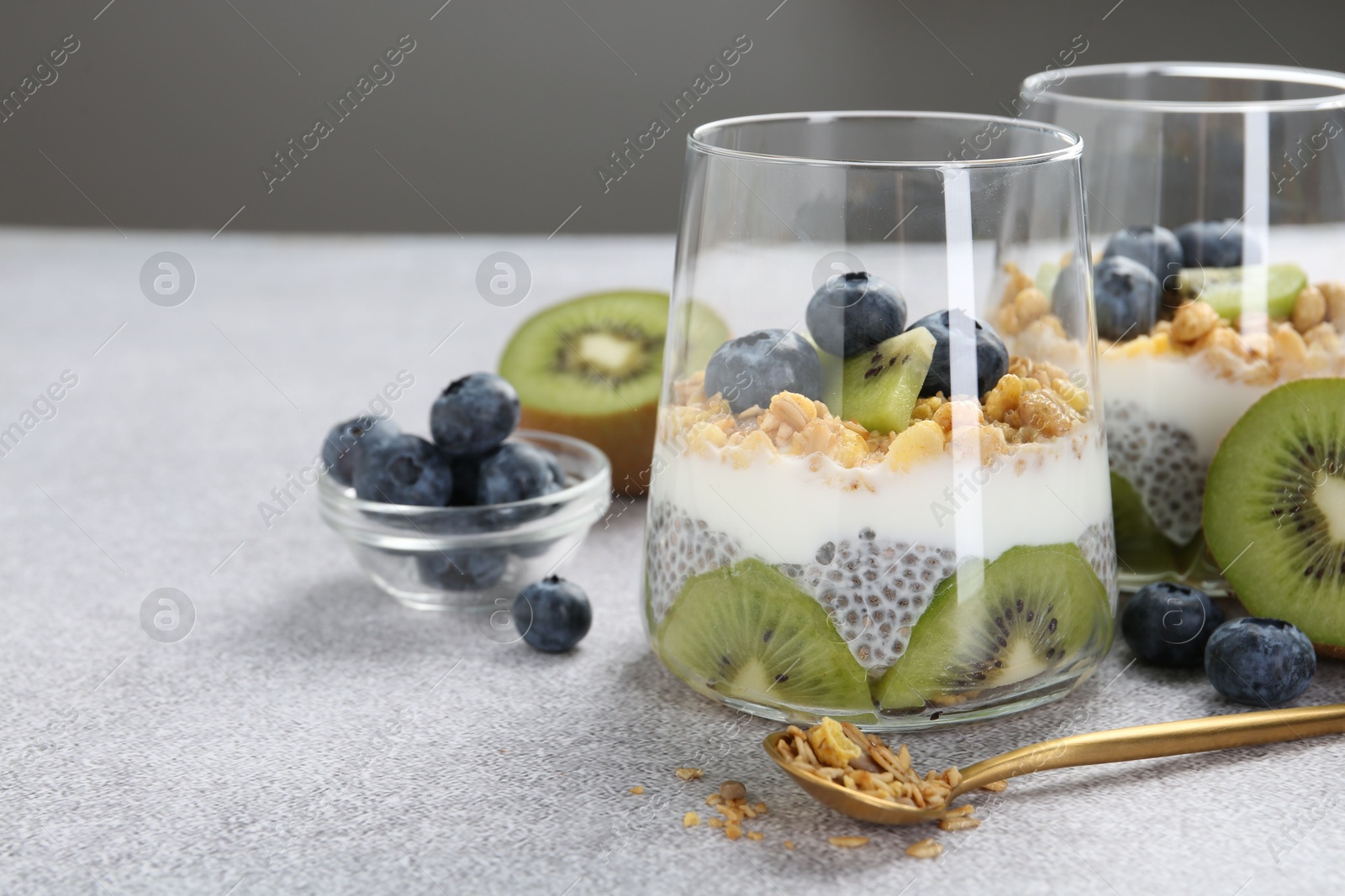 Superfood. Delicious dessert with chia seeds, yogurt, granola, blueberries and kiwi on light grey table, closeup. Space for text Photo of Superfood. Delicious dessert with chia seeds, yogurt, granola, blueberries and kiwi on light grey table, closeup. Space for text