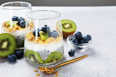 Photo of Delicious dessert with chia seeds, yogurt, granola, blueberries and kiwi on light grey table, closeup. Superfood