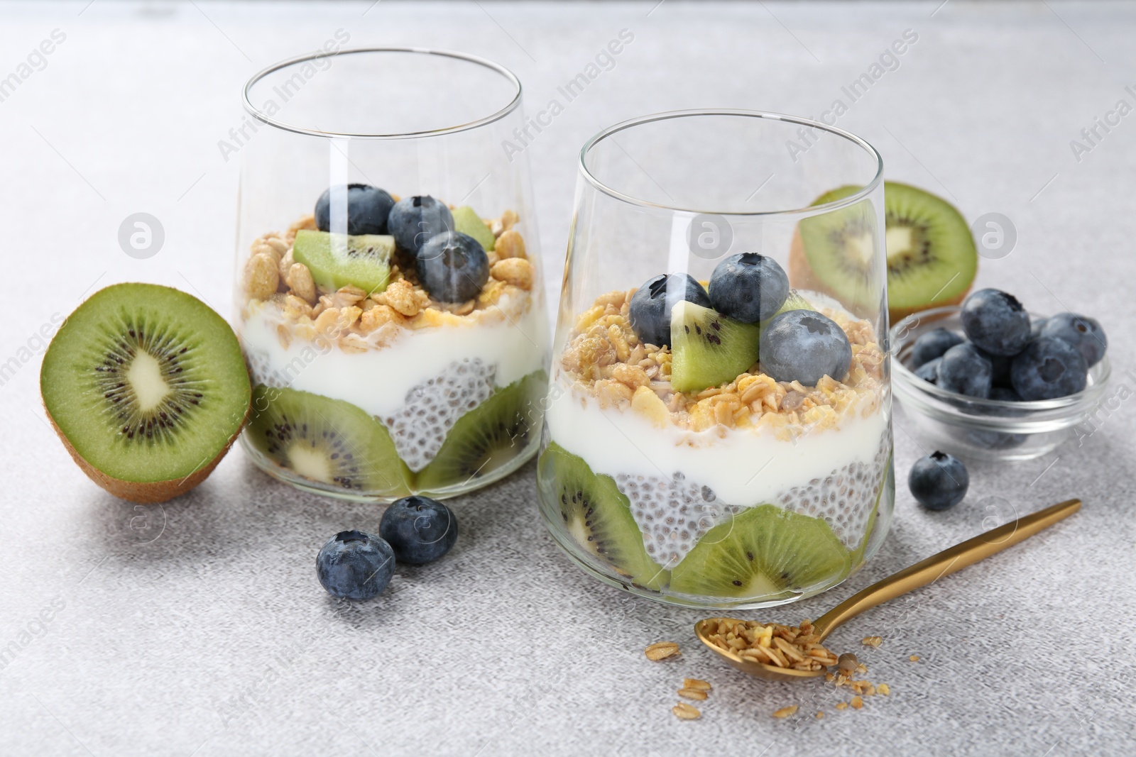 Delicious dessert with chia seeds, yogurt, granola, blueberries and kiwi on light grey table, closeup. Superfood Photo of Delicious dessert with chia seeds, yogurt, granola, blueberries and kiwi on light grey table, closeup. Superfood