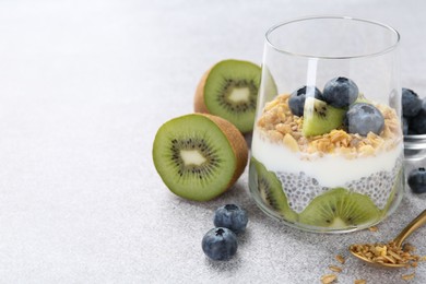 Photo of Superfood. Delicious dessert with chia seeds, yogurt, granola, blueberries and kiwi on light grey table, closeup. Space for text