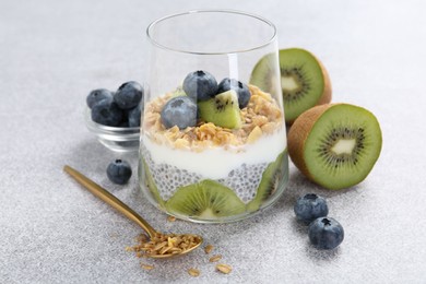 Photo of Delicious dessert with chia seeds, yogurt, granola, blueberries and kiwi on light grey table, closeup. Superfood