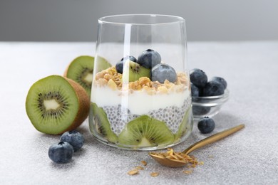 Photo of Delicious dessert with chia seeds, yogurt, granola, blueberries and kiwi on light grey table, closeup. Superfood