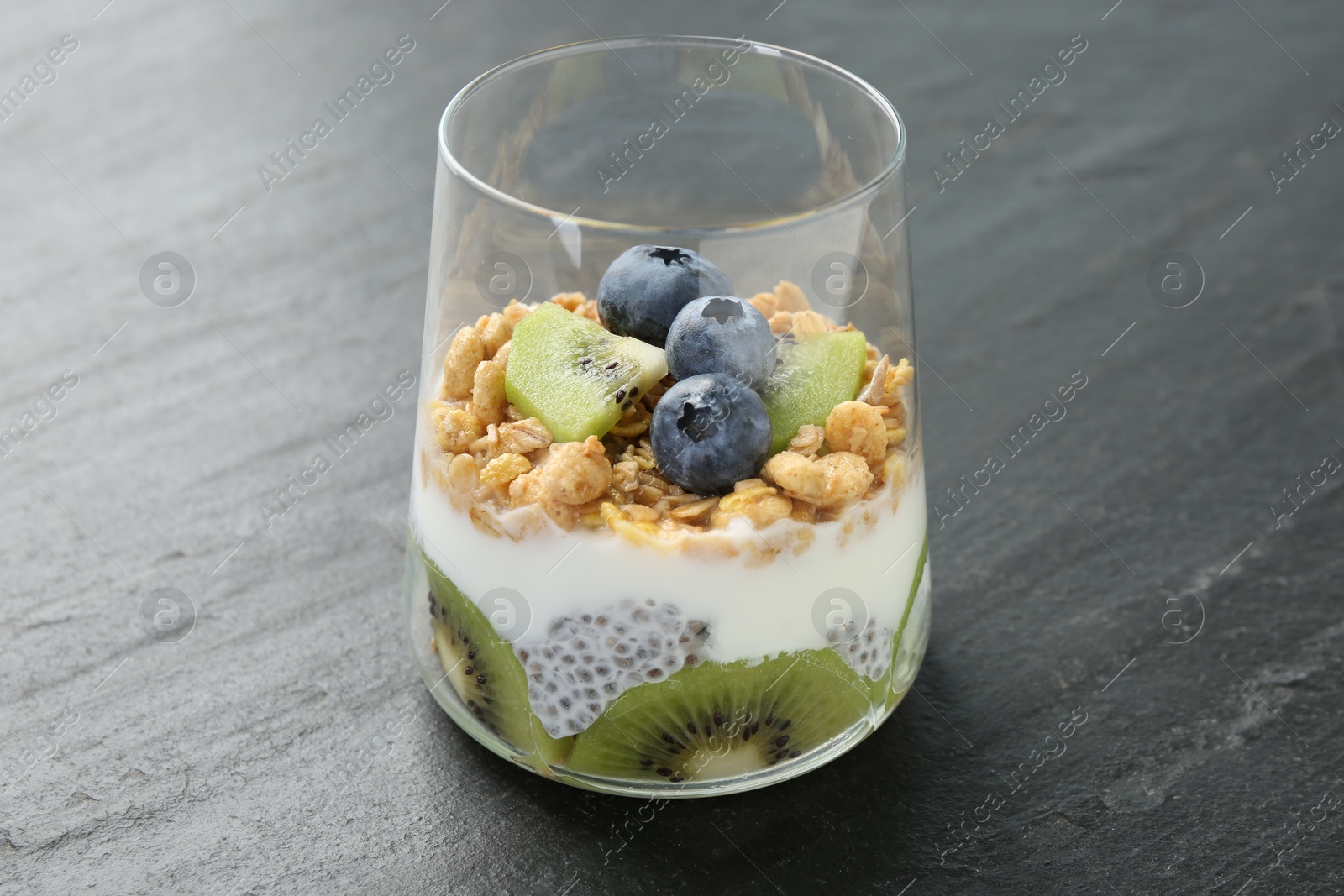 Delicious dessert with chia seeds, yogurt, granola, blueberries and kiwi in glass on grey table, closeup. Superfood Photo of Delicious dessert with chia seeds, yogurt, granola, blueberries and kiwi in glass on grey table, closeup. Superfood