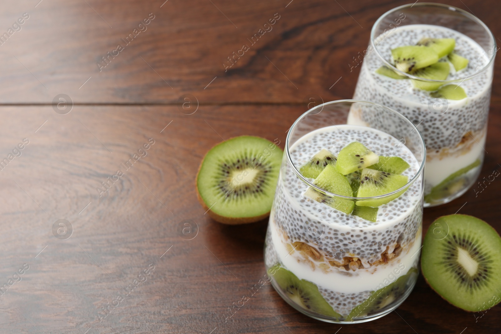 Superfood. Delicious dessert with chia seeds, yogurt, granola and kiwi on wooden table, closeup. Space for text Photo of Superfood. Delicious dessert with chia seeds, yogurt, granola and kiwi on wooden table, closeup. Space for text