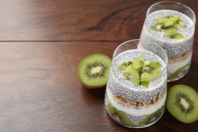 Photo of Superfood. Delicious dessert with chia seeds, yogurt, granola and kiwi on wooden table, closeup. Space for text