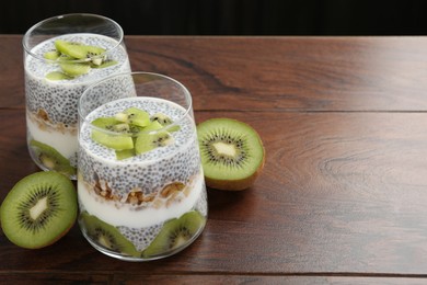 Photo of Superfood. Delicious dessert with chia seeds, yogurt, granola and kiwi on wooden table, closeup. Space for text