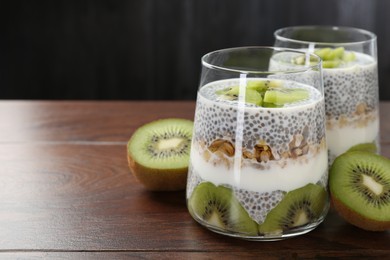 Photo of Superfood. Delicious dessert with chia seeds, yogurt, granola and kiwi on wooden table, closeup. Space for text