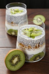 Photo of Delicious dessert with chia seeds, yogurt, granola and kiwi on wooden table, closeup. Superfood