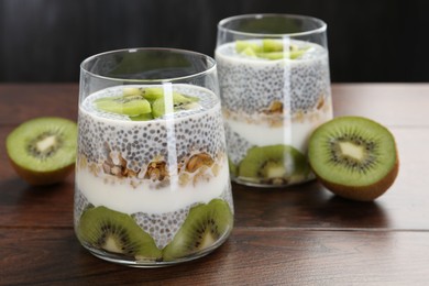 Photo of Delicious dessert with chia seeds, yogurt, granola and kiwi on wooden table, closeup. Superfood