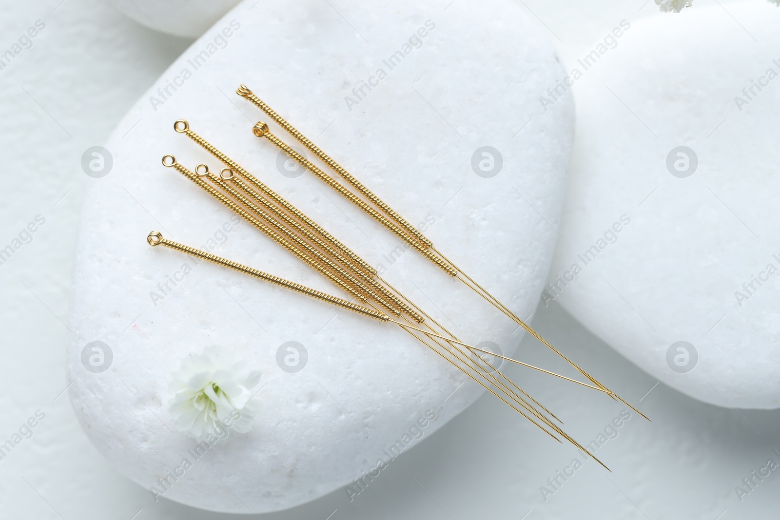 Acupuncture needles, pebble stones and flower bud on white table, flat lay Photo of Acupuncture needles, pebble stones and flower bud on white table, flat lay