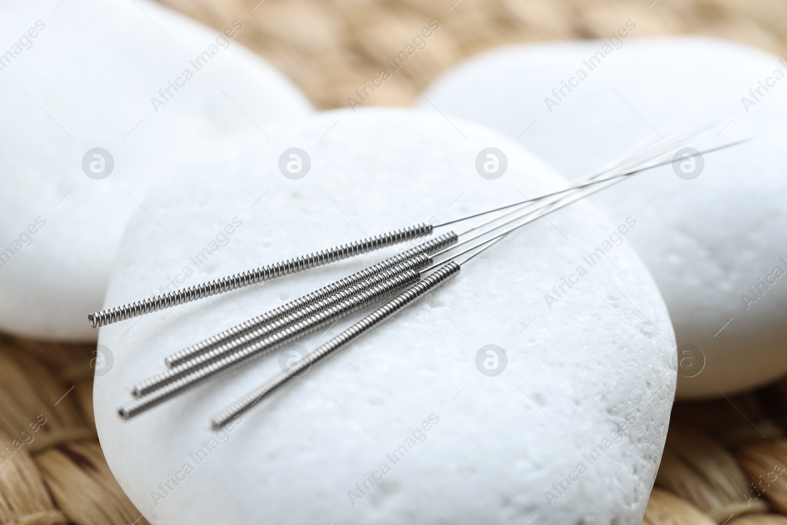Acupuncture needles and pebble stones on wicker surface, closeup Photo of Acupuncture needles and pebble stones on wicker surface, closeup