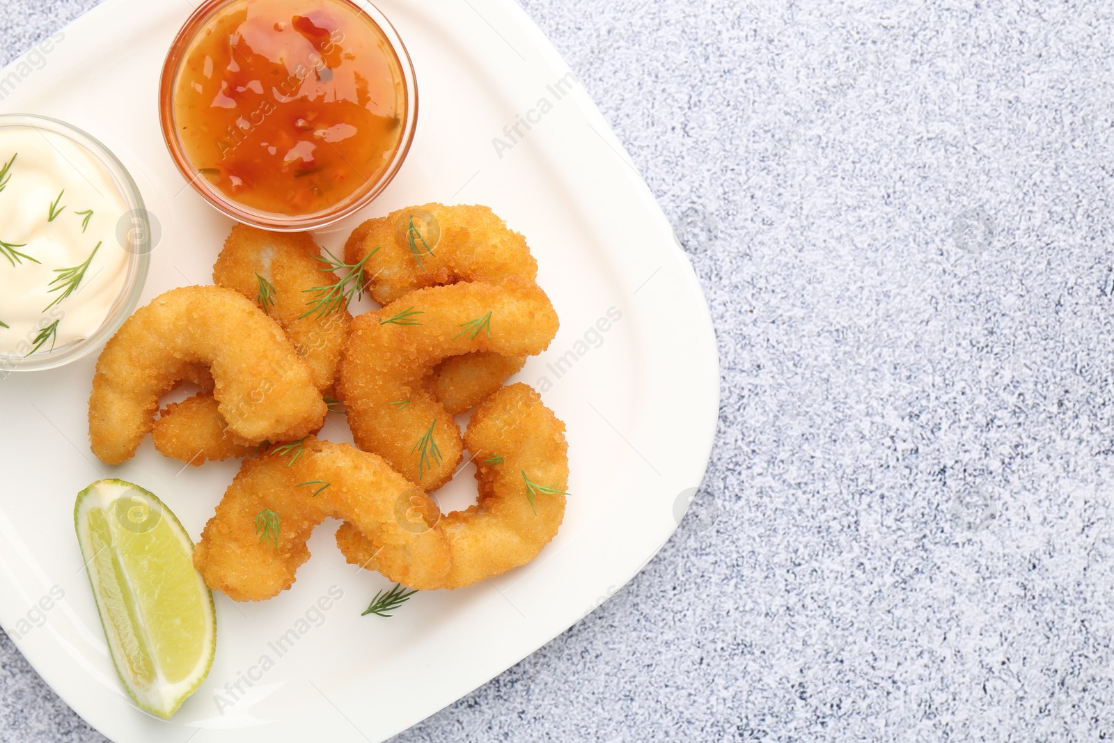 Tasty tempura shrimps, lime and sauces on grey textured table, top view. Space for text Photo of Tasty tempura shrimps, lime and sauces on grey textured table, top view. Space for text